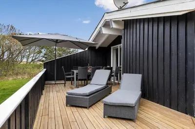 a deck with a table and chairs and an umbrella at LK2126-Lokken-Jorginesvej-4 in Løkken