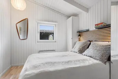 a white bedroom with a bed and a mirror at LK2126-Lokken-Jorginesvej-4 in Løkken