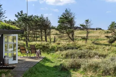 a house with two chairs sitting on a porch at BL1235-Blokhus-Malinsvej-9 in Blokhus