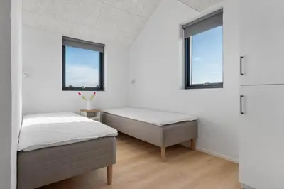 two beds in a white room with two windows at LK2144-Lokken-Kringelbaekvej-31 in Løkken