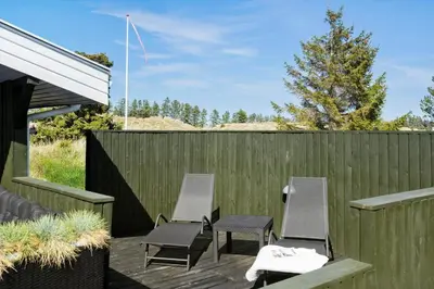 a patio with three chairs and a fence at BL1706-Blokhus-Bloksbjerg-91 in Blokhus