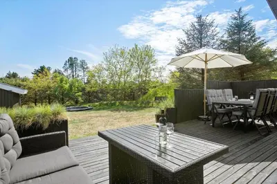 a wooden deck with a table and an umbrella at BL1706-Blokhus-Bloksbjerg-91 in Blokhus