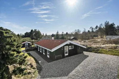 a small house with a red roof on a gravel driveway at BL1706-Blokhus-Bloksbjerg-91 in Blokhus