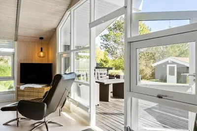 a living room with a chair and a sliding glass door at BL1706-Blokhus-Bloksbjerg-91 in Blokhus