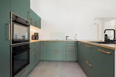a kitchen with green cabinets and a black oven at LK2146-Lokken-Redningsstien-2 in Løkken