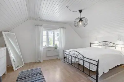 a white bedroom with a bed and a chandelier at BL1454-Pandrup-Rodhusvej-215 in Pandrup