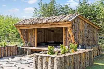 a wooden shed with a table in a garden at BL1092-Saltum-Doggerbanke-2 in Saltum
