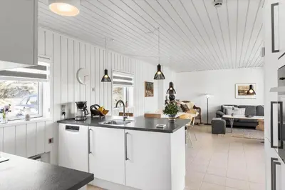 a kitchen with white cabinets and a living room at BL1349-Pandrup-Rodhus-Klitvej-217 in Pandrup
