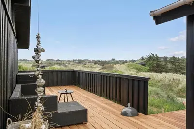 a balcony with a chair and a table on a deck at BL1450-Blokhus-Klitvejen-99 in Blokhus