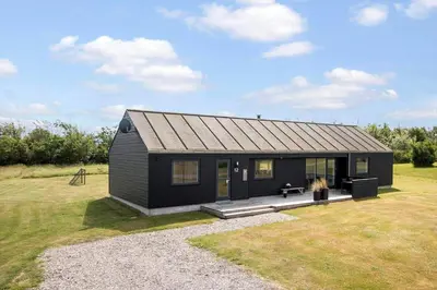 a black tiny house sitting on top of a field at LK2167-Lokken-Kringelbaekvej-12 in Løkken