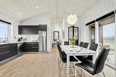 a kitchen with a white table and black chairs at LK2167-Lokken-Kringelbaekvej-12 in Løkken