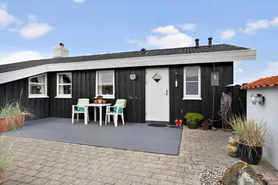 a black shed with a table and chairs on a patio at BL1587-Blokhus-Karnoevej-1 in Blokhus