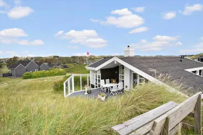a white house with a porch on a beach at BL1587-Blokhus-Karnoevej-1 in Blokhus
