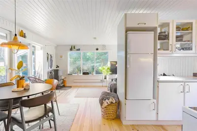 a kitchen with a table and a white refrigerator at BL946-Blokhus-Graevlingevej-8 in Blokhus