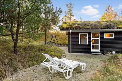 two white chairs sitting outside of a house at BL946-Blokhus-Graevlingevej-8 in Blokhus