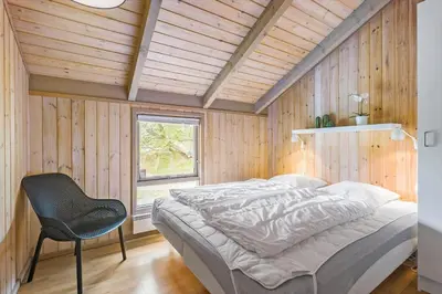 a bedroom with a bed and a chair in it at BL1438-Blokhus-Bloksbjerg-82 in Blokhus