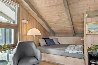 a small bedroom with a bed and a chair at BL1438-Blokhus-Bloksbjerg-82 in Blokhus