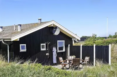 a black house with a table and chairs in front of it at BL819-Blokhus-Pirupshvarrekrogen-2 in Blokhus