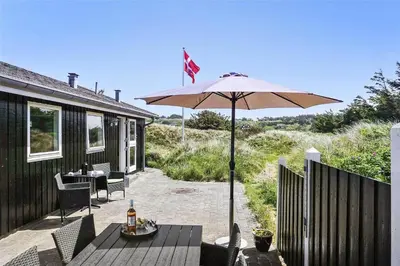 a patio with a table and an umbrella at BL819-Blokhus-Pirupshvarrekrogen-2 in Blokhus