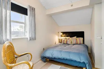 a bedroom with a bed and a window and a chair at BL1425-Blokhus-N-S-Larsensvej-6 in Blokhus