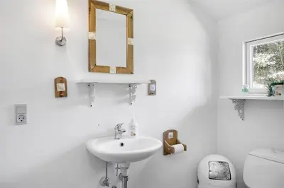 a bathroom with a sink and a mirror and a toilet at BL445-Blokhus-Bag-Hojen-65 in Blokhus