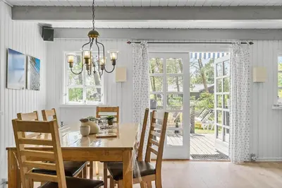 a dining room with a table and chairs and a chandelier at BL445-Blokhus-Bag-Hojen-65 in Blokhus