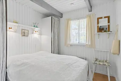 a white bedroom with a bed and a window at BL445-Blokhus-Bag-Hojen-65 in Blokhus