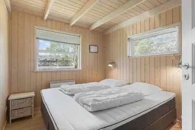 a bedroom with a bed in a room with two windows at BL1382-Blokhus-Gyvelvej-20-A in Blokhus