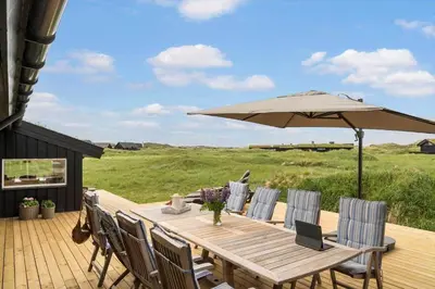 a wooden table with an umbrella on a deck at BL1020-Pandrup-Hunetorp-Klitvej-257 in Pandrup