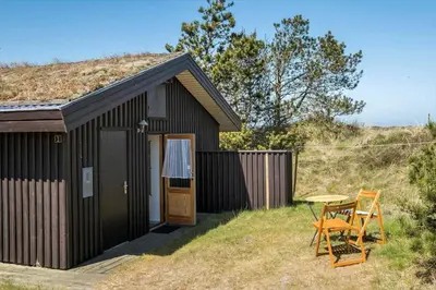 a small black shed with a table and a chair at BL1225-Pandrup-Flaskehalsen-1 in Pandrup
