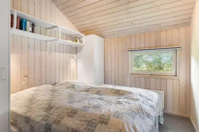 a small bedroom with a bed and a window at BL1255-Pandrup-Rodhusparken-63 in Pandrup