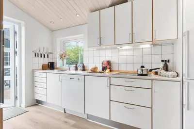 a white kitchen with white cabinets and a window at BL1396-Blokhus-Laerkevej-8 in Blokhus