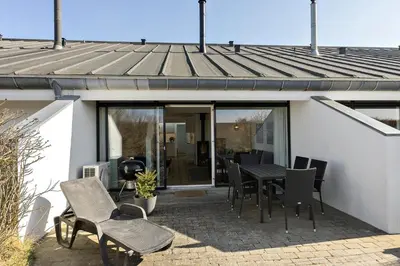 a patio with a table and chairs and a grill at BL1538-Blokhus-Ferren-42 in Blokhus