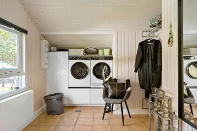 a laundry room with a washing machine and a chair at BL1566-Saltum-Lille-Fiskerbanke-3 in Saltum
