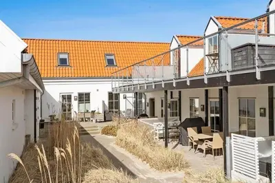 a building with a balcony and tables and chairs at BL1582-Blokhus-Strandvejen-14-Lejl-11 in Blokhus