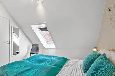 a bedroom with a bed with blue sheets and a chair at BL1582-Blokhus-Strandvejen-14-Lejl-11 in Blokhus