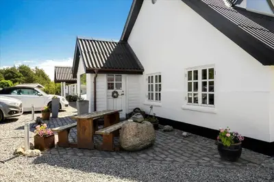 a white house with a bench in front of it at BL1674-Pandrup-Kystvejen-19 in Pandrup