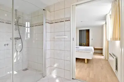 a bathroom with a walk in shower next to a bed at BL1548-Blokhus-Paa-Bakken-10 in Blokhus