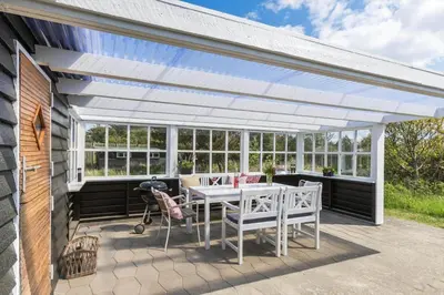 a white pergola on a patio with a table and chairs at BL1548-Blokhus-Paa-Bakken-10 in Blokhus