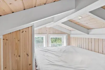 a bedroom with a white bed and wooden walls at BL959-Saltum-Nordvestvej-6 in Saltum