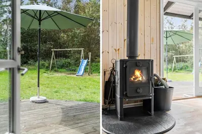 a fireplace and an umbrella next to a house at BL959-Saltum-Nordvestvej-6 in Saltum