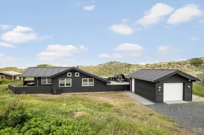 a black house with a garage and mountains in the background at BL1470-Saltum-Faaborgvej-6 in Saltum