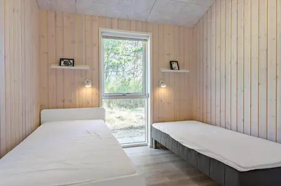 two beds in a room with a window at BL1783-Blokhus-Lyngbakkevej-9 in Blokhus