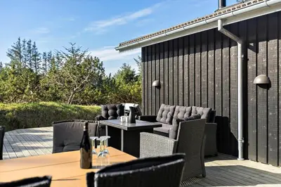 a patio with chairs and a table and a fence at BL1783-Blokhus-Lyngbakkevej-9 in Blokhus