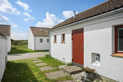 a white house with a red door in a yard at BL1775-Pandrup-Rodhus-Klitvej-335 in Pandrup