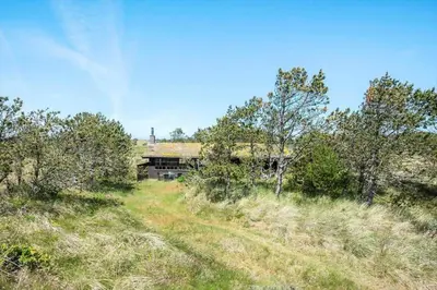 a building in the middle of a field with trees at BL1570-Pandrup-Flaskehalsen-13-A in Pandrup
