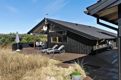 a black house with chairs and a deck at BL852-Saltum-Revlingevej-14 in Saltum