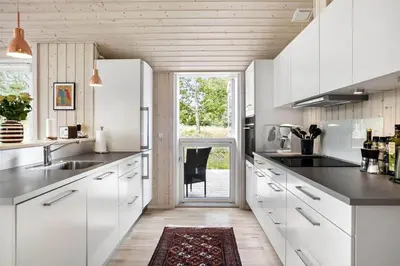 a kitchen with white cabinets and a large window at BL377-Blokhus-Maxvej-9 in Blokhus