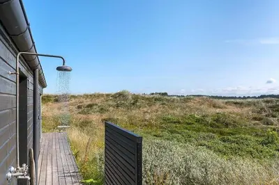 a house with a wooden walkway next to a field at BL1231-Pandrup-Lunen-54 in Pandrup