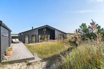 a black house with a wooden walkway in front of it at BL1231-Pandrup-Lunen-54 in Pandrup